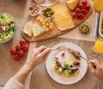 Overhead view of a cheese platter with fresh salad and juice, perfect for a gourmet lunch setting.